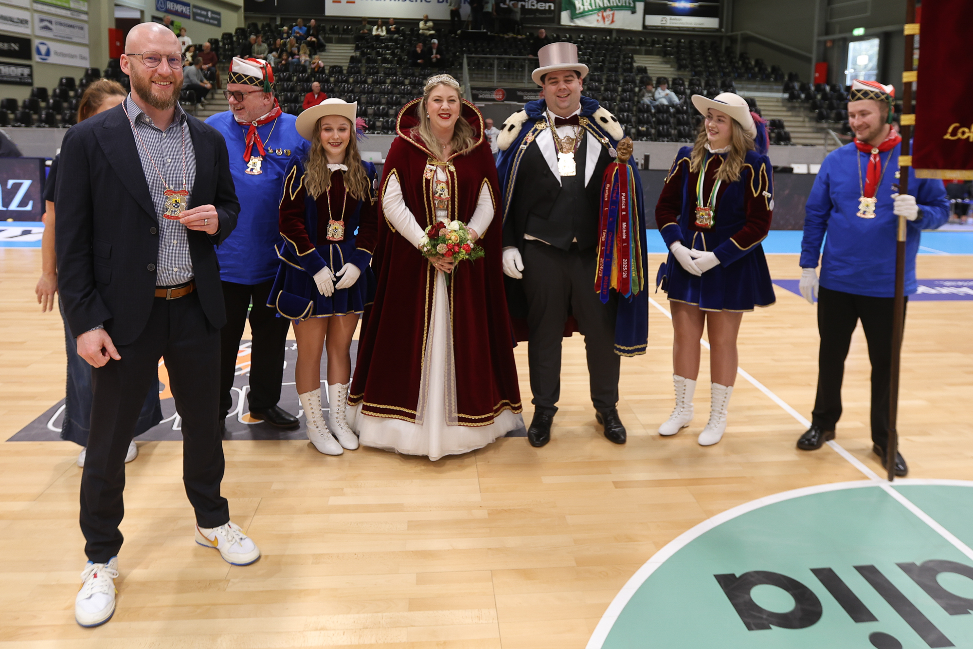 Eine fröhliche Festgruppe in farbenfrohen Umhängen und Kostümen in einer Halle