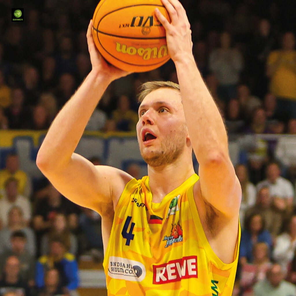 Ein konzentrierter Basketballspieler im gelben Trikot bereitet sich auf einen Wurf vor