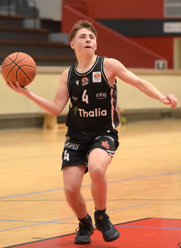 Ein junger Basketballspieler im schwarzen Trikot mit konzentriertem Gesichtsausdruck