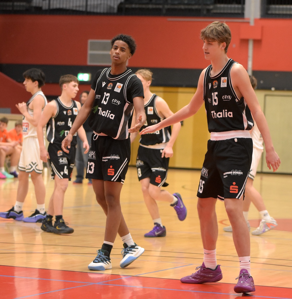 Zwei junge Basketballspieler im schwarzen Trikot geben sich beim Spiel High Five