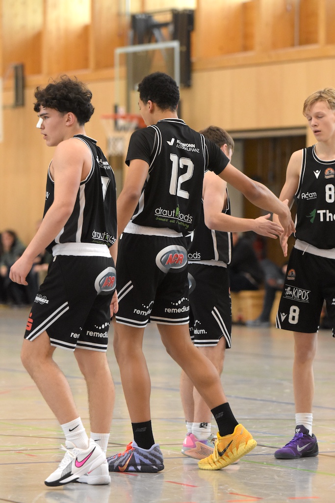 Vier junge Basketballspieler im schwarzen Trikot wirken konzentriert auf dem Spielfeld