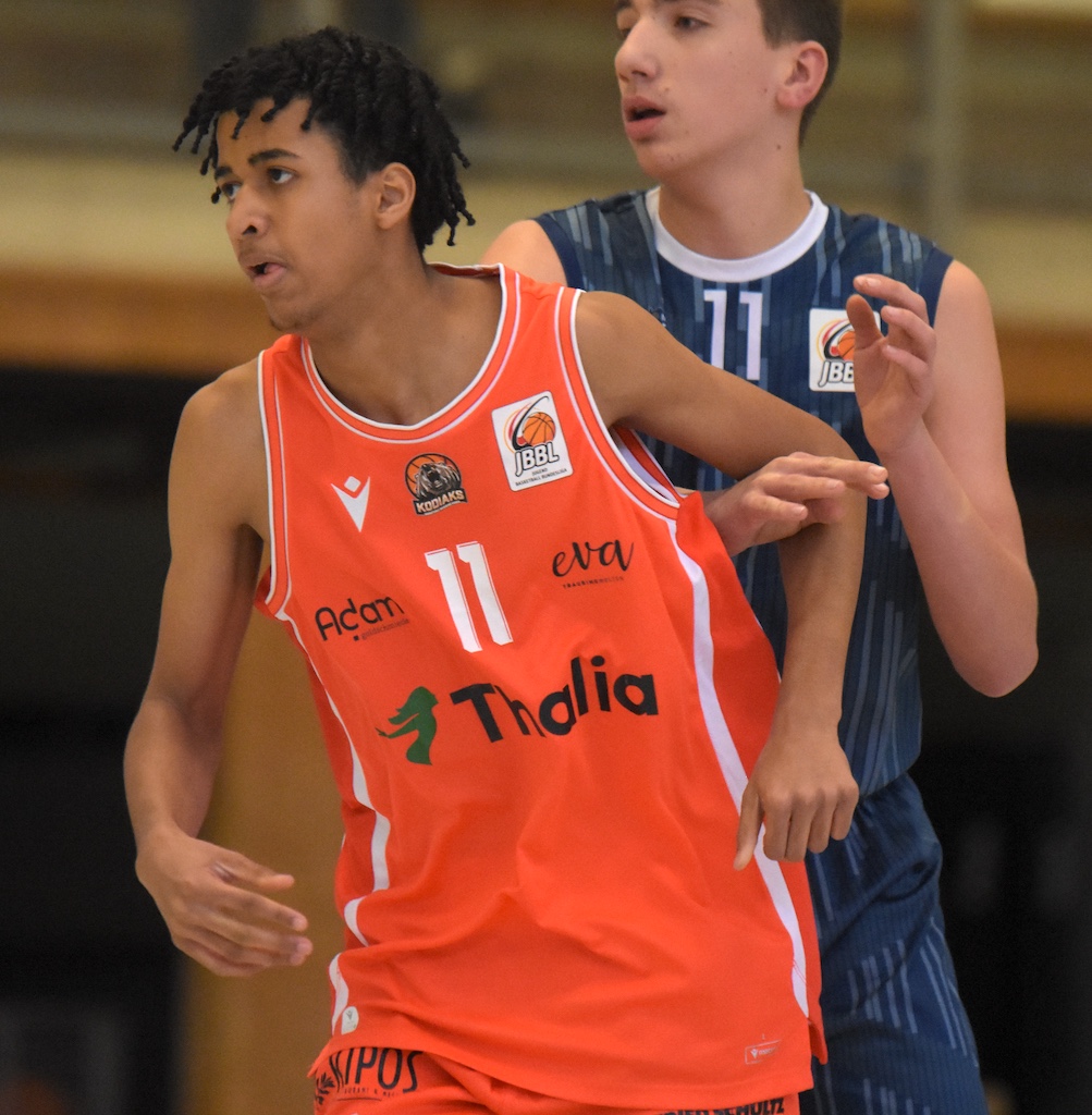 Ein junger Basketballspieler im orangefarbenen Trikot mit konzentriertem Gesichtsausdruck