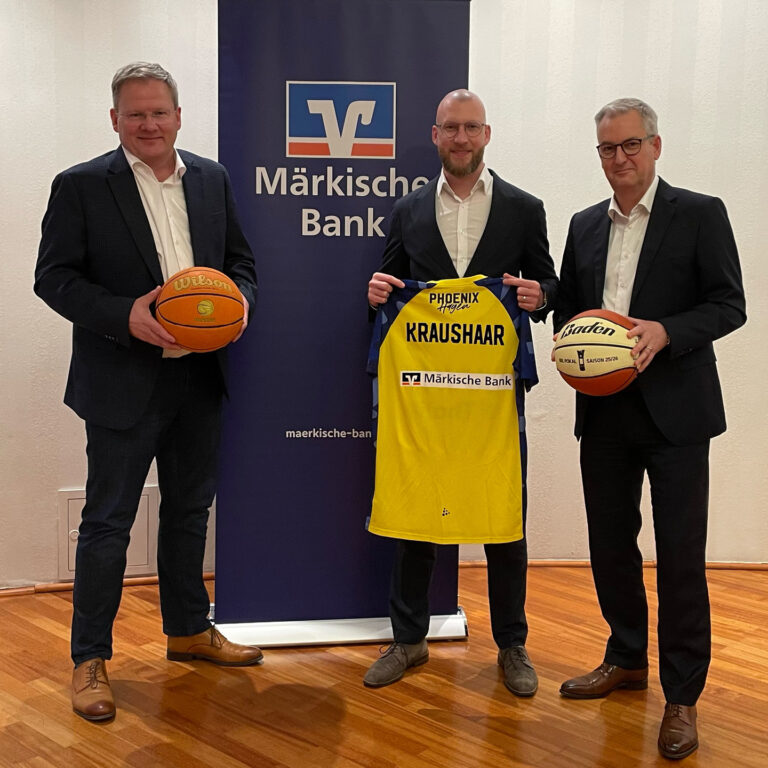 Drei lächelnde Männer im Anzug halten Basketball und gelbes Trikot vor Bank-Logo