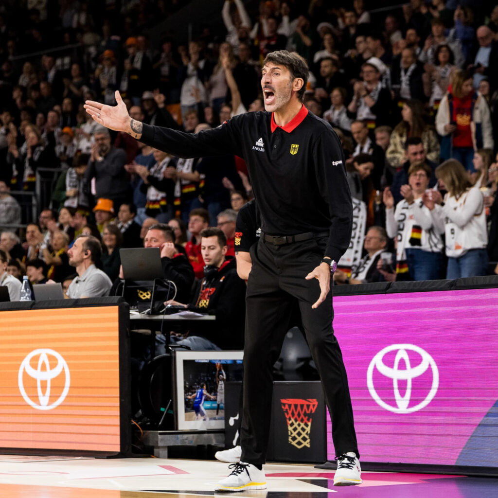 Ein großgewachsener Mann in schwarzer Sportkleidung gestikuliert energisch am Spielfeldrand