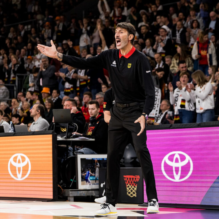 Ein großgewachsener Mann in schwarzer Sportkleidung gestikuliert energisch am Spielfeldrand