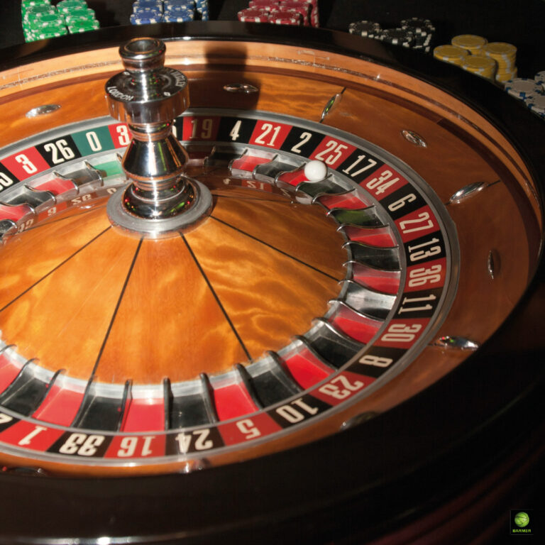 Holzfarbenes Roulette mit rot schwarzen Feldern und Spieljetons im Hintergrund