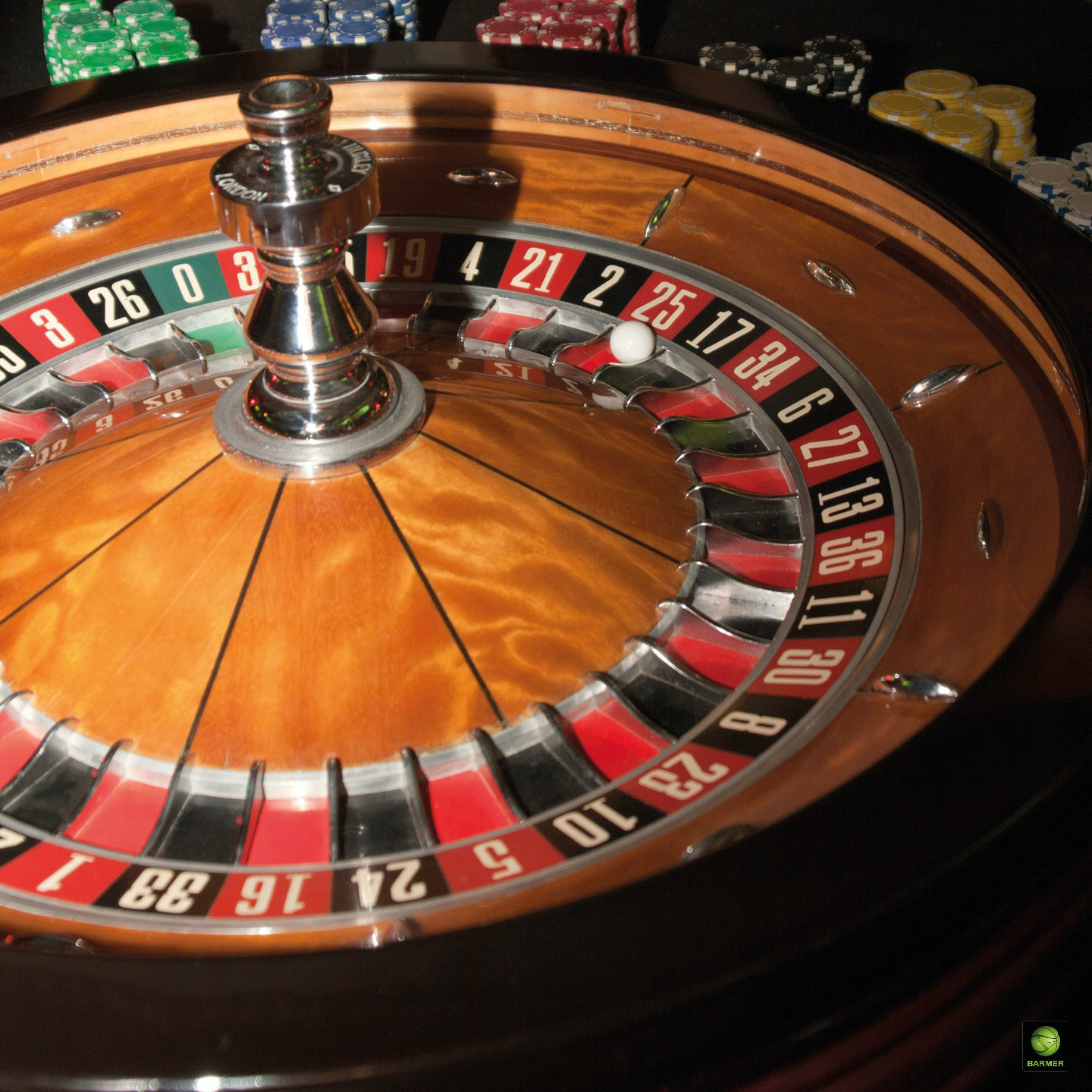 Holzfarbenes Roulette mit rot schwarzen Feldern und Spieljetons im Hintergrund