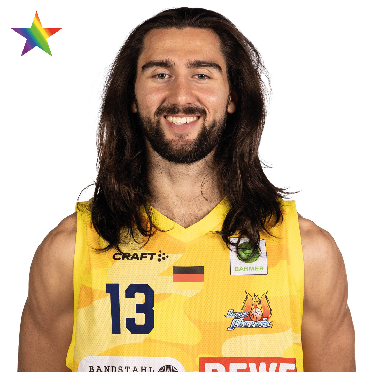 Ein junger Mann mit langen braunen Haaren und Bart lächelt freundlich im gelben Basketballtrikot