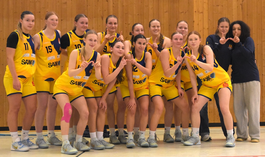 Frauen Basketballteam in gelben Trikots posiert lachend und zeigt freundliche Gesten