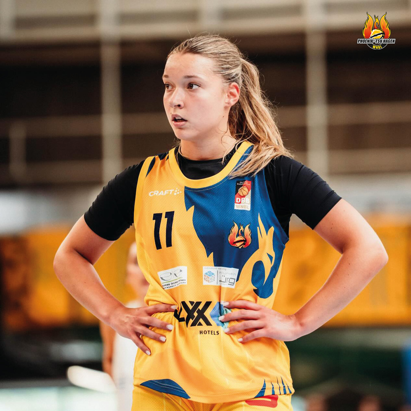 Junge Frau im gelben Basketballtrikot mit entschlossener Miene und blonden Haaren