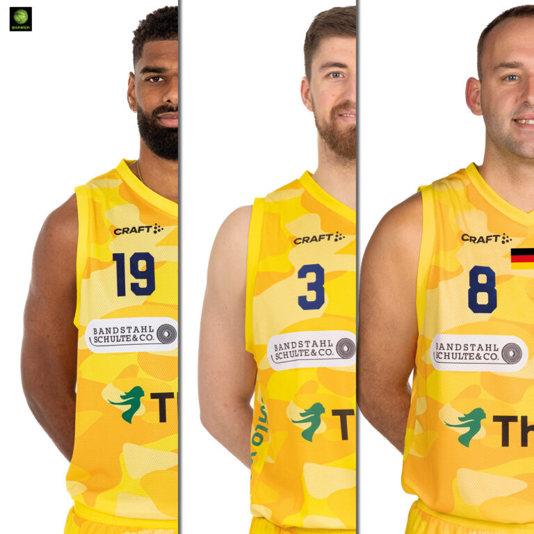 Drei männliche Basketballspieler in gelben Trikots mit ernsten Gesichtern