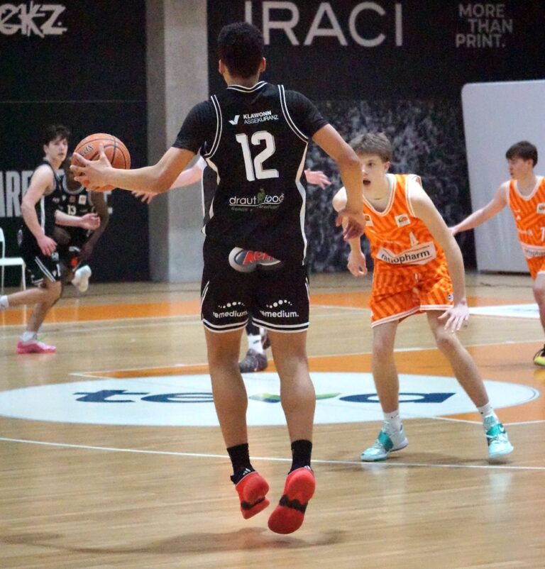 Ein Basketballspieler mit schwarzem Trikot und sichtbarer Nummer 12 passt den Ball