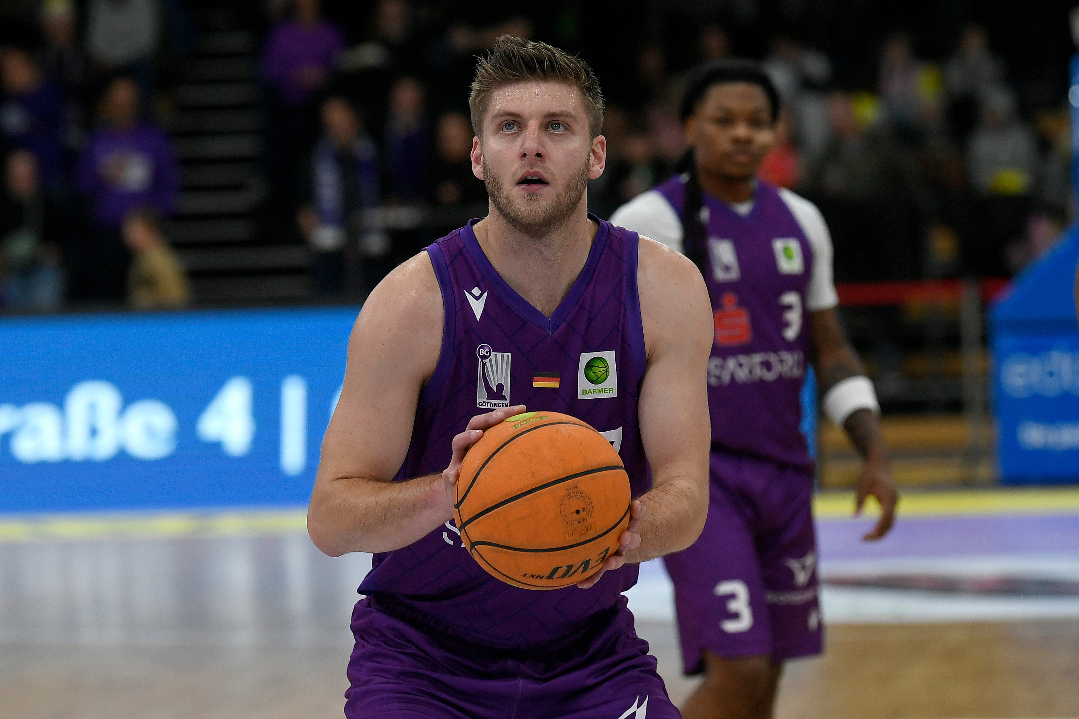 Ein konzentrierter Basketballspieler im lila Trikot bereitet einen Freiwurf vor