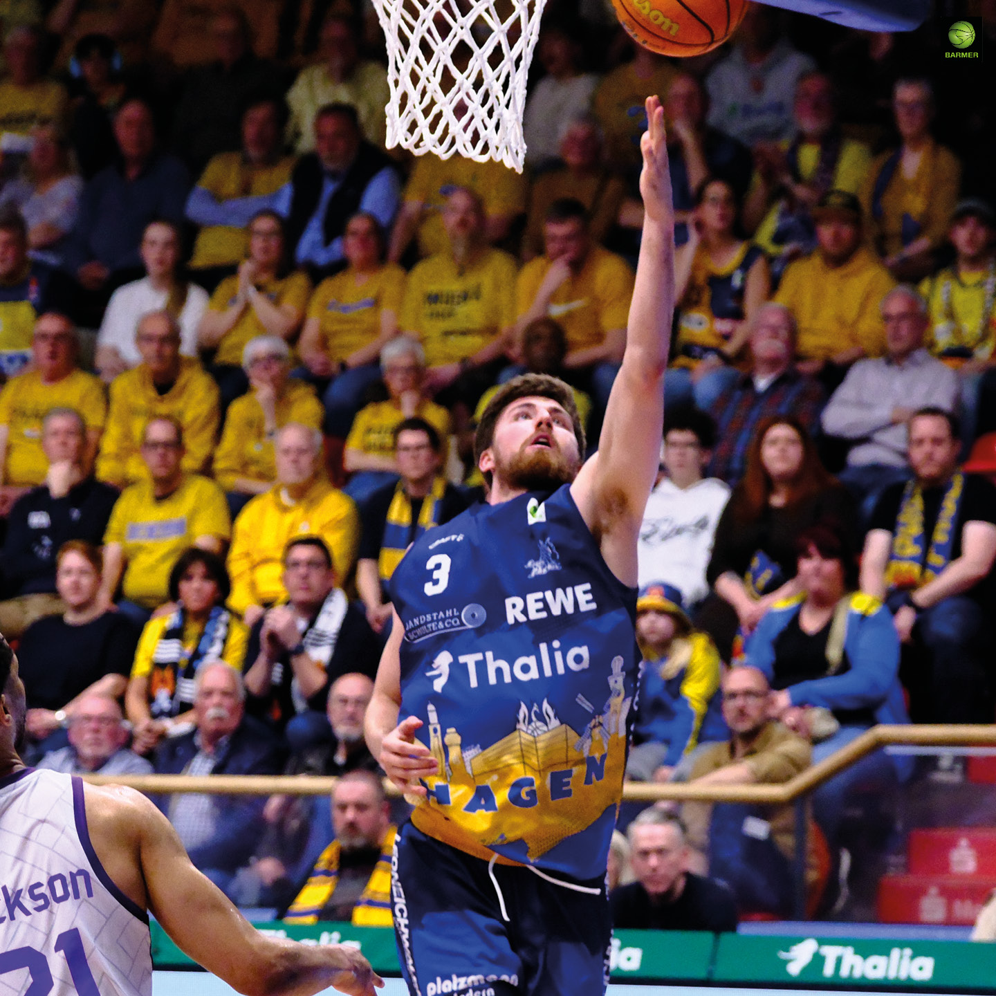 Ein Basketballspieler mit entschlossenem Gesichtsausdruck wirft im gelben Trikot zum Korb