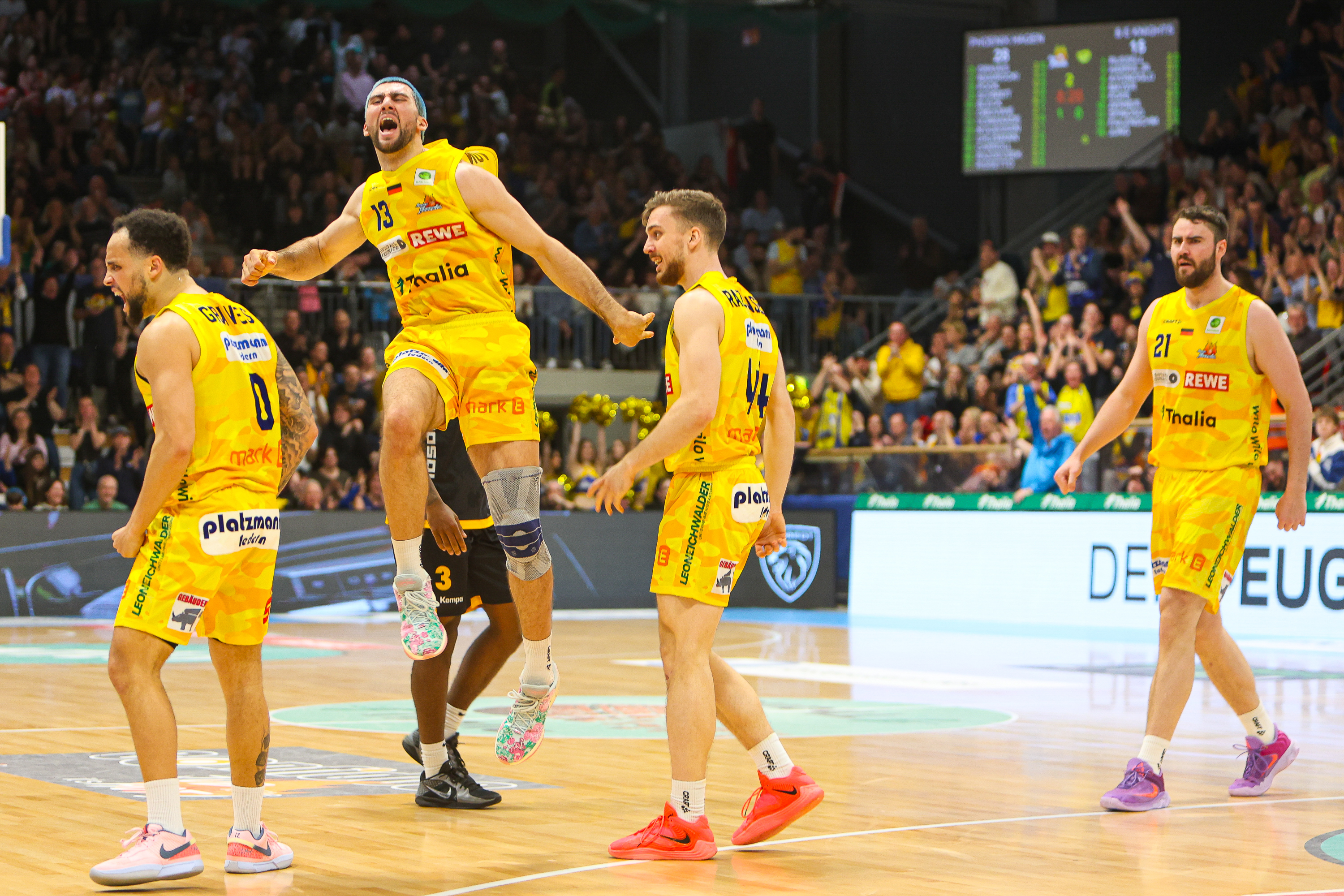Vier Basketballspieler im gelben Trikot jubeln lachend und wirken sehr energiegeladen