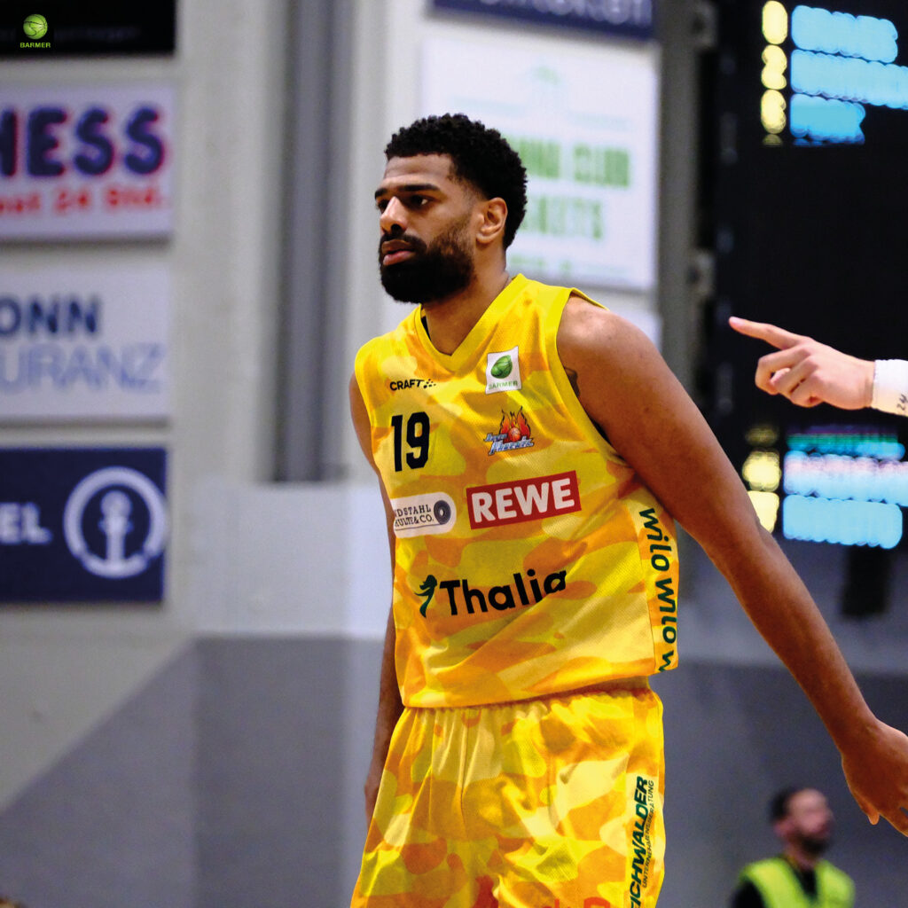 Ein Basketballspieler mit nachdenklichem Blick trägt ein gelbes Trikot mit der Nummer 19