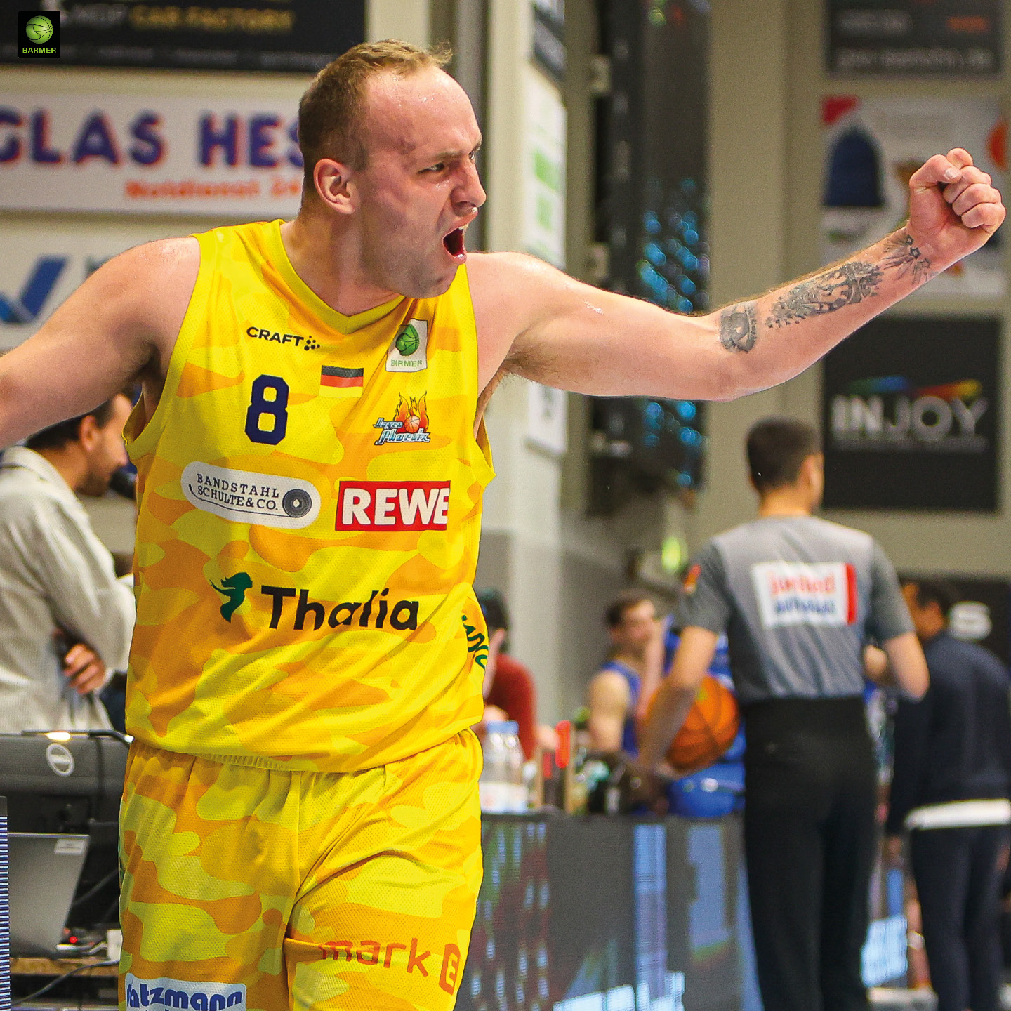 Ein kräftiger Basketballspieler im gelben Trikot jubelt emotional mit erhobener Faust