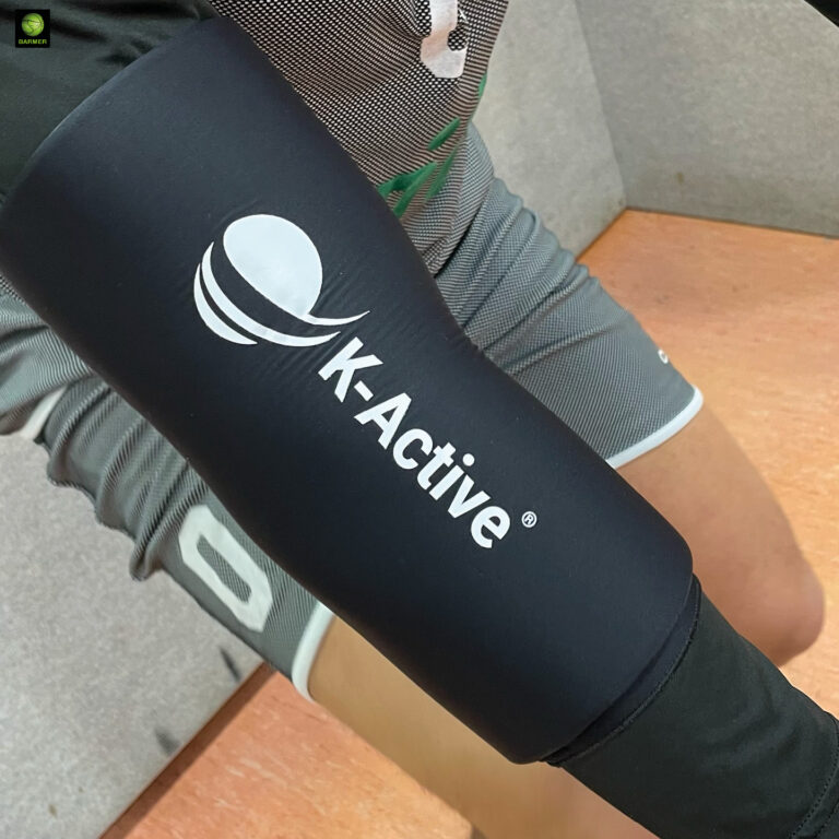 Eine Person trägt eine schwarze K-ACTIVE Bandage am Arm und graue Sportkleidung