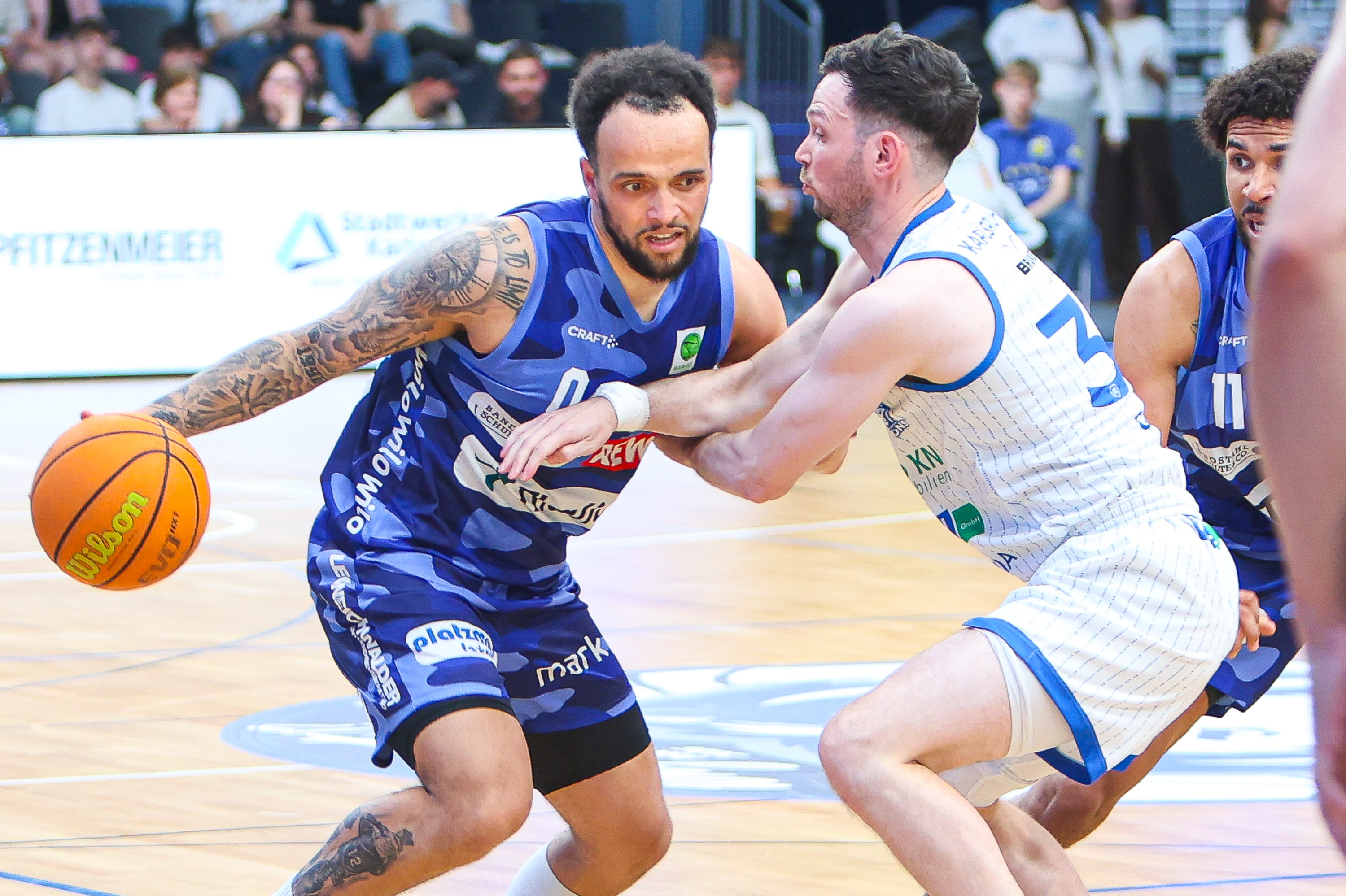 Zwei Basketballspieler im blauen und weißen Trikot kämpfen energisch um den Ball