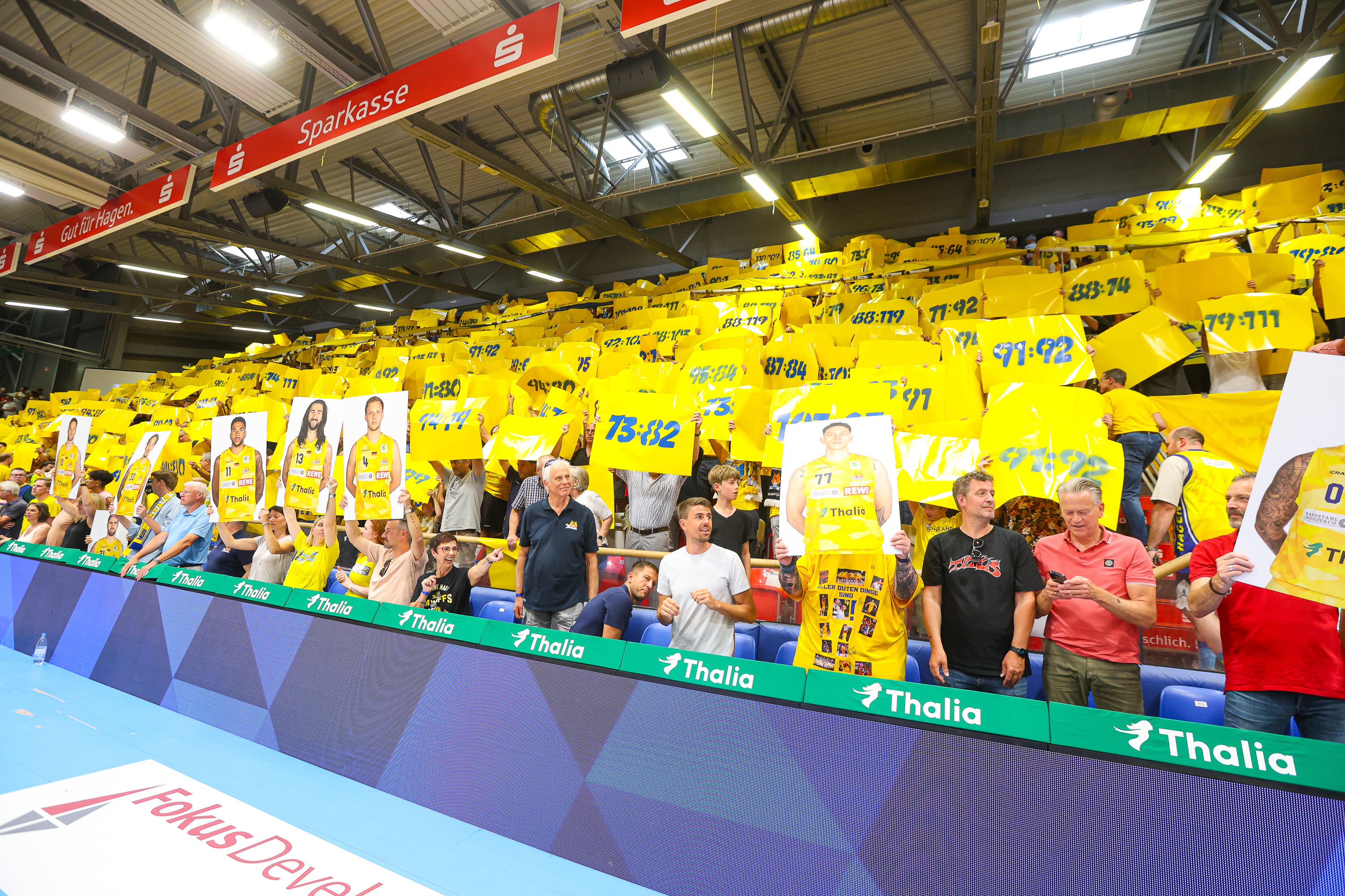 Jubelnde Fans in Gelb mit Bannern und Plakaten in einer Sporthalle