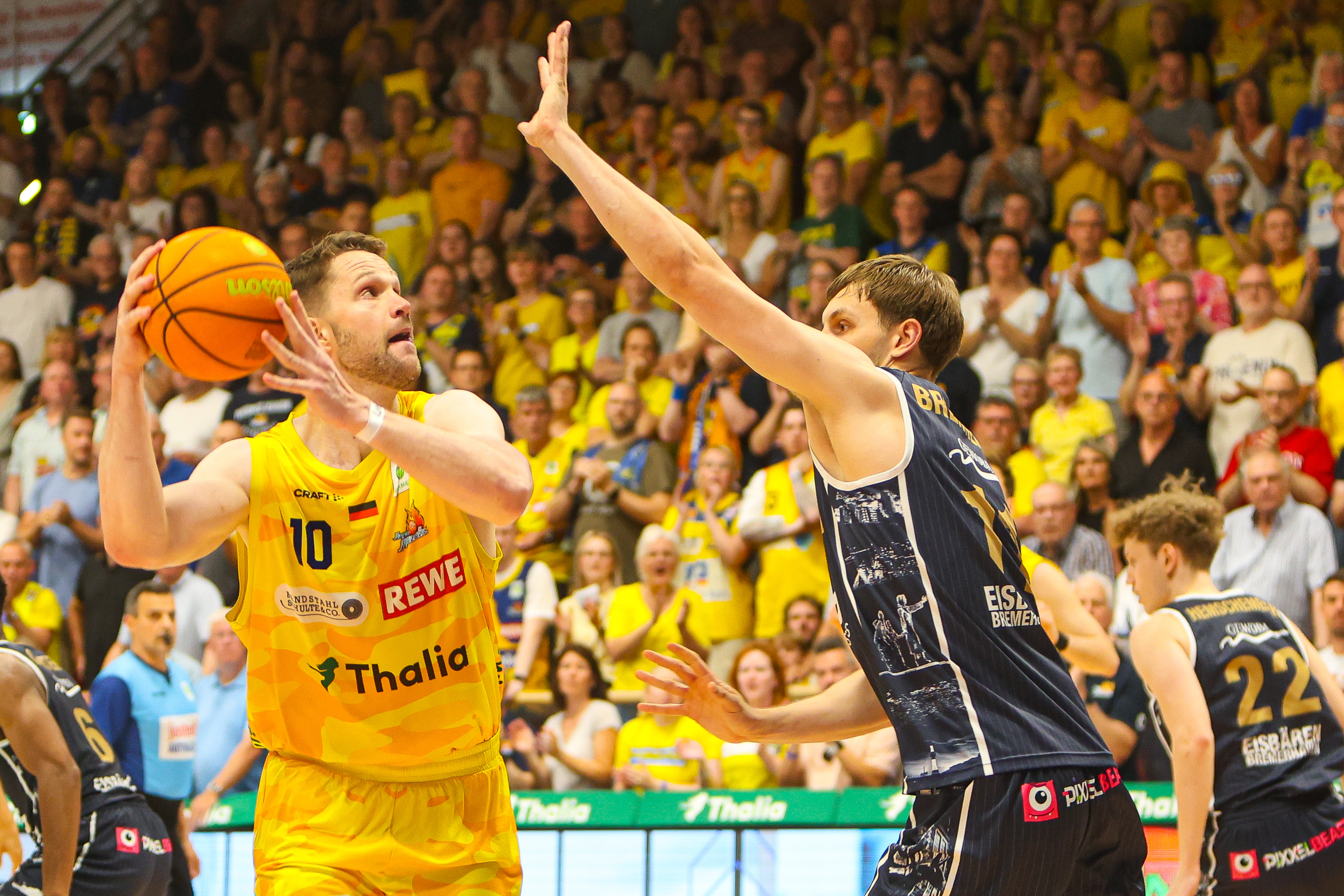 Zwei Basketballspieler fokussiert gelb und blau im Sprung vor Fans