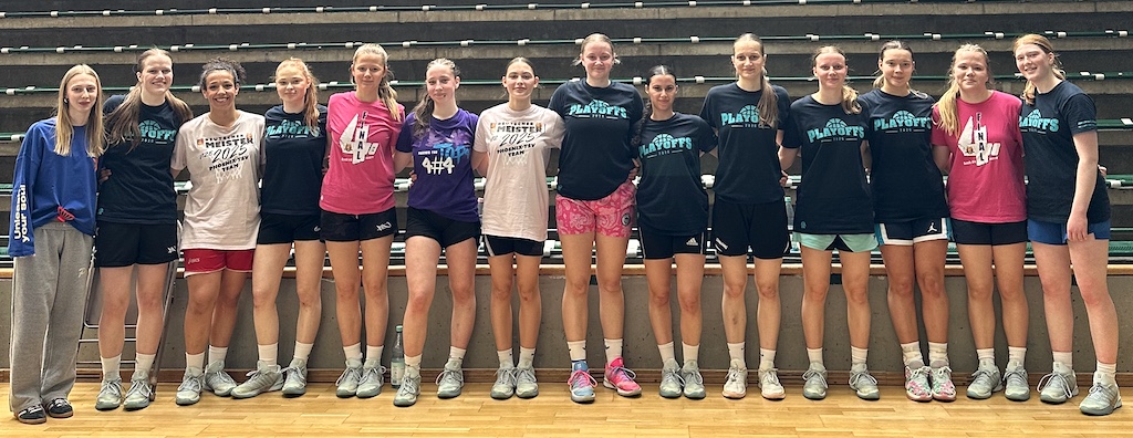 Eine Gruppe junger Frauen lächelt gemeinsam in Sportkleidung vor Tribünen
