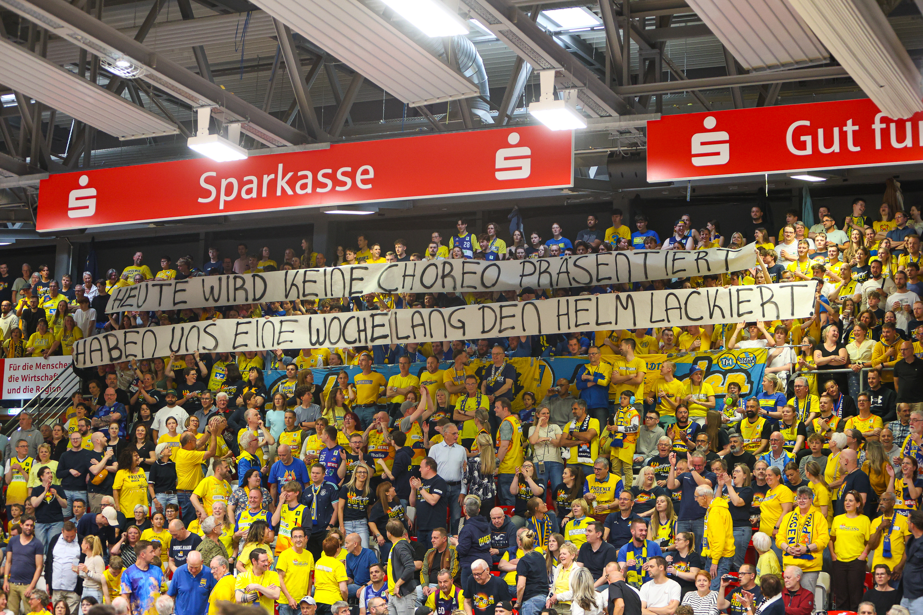 Jubelnde Fans in Gelb und Blau halten großes Banner in der Halle