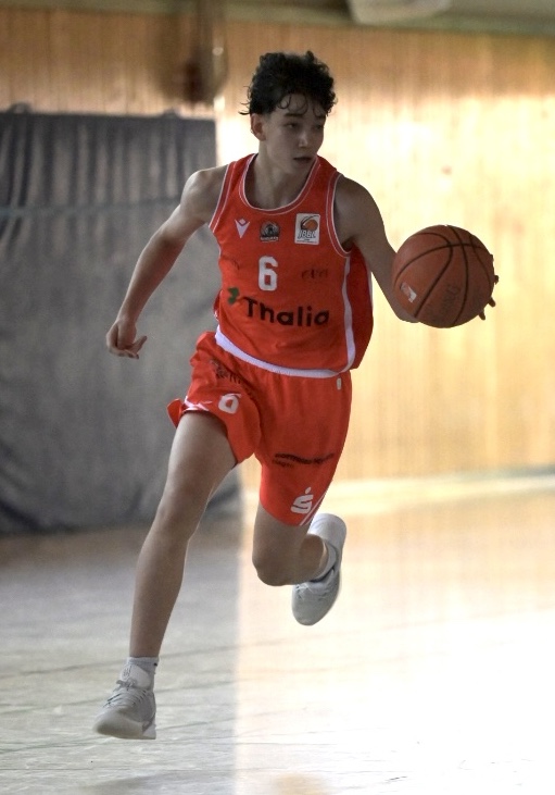 Fokussierter Basketballspieler im roten Trikot 6 dribbelt den Ball im Lauf