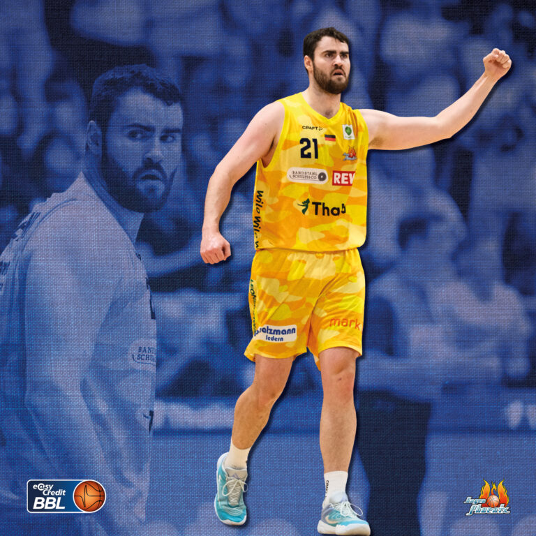 Jubelnder Basketballspieler in gelbem Trikot 21 vor blauem Hintergrund
