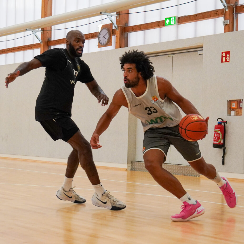 Ein Basketballspieler im Trikot mit Nummer 33 dribbelt an einem Gegner vorbei