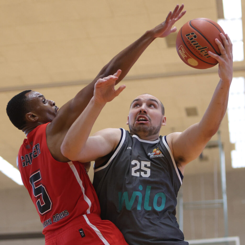 Zwei Basketballspieler in Rot und Grau kaempfen konzentriert um den Ball