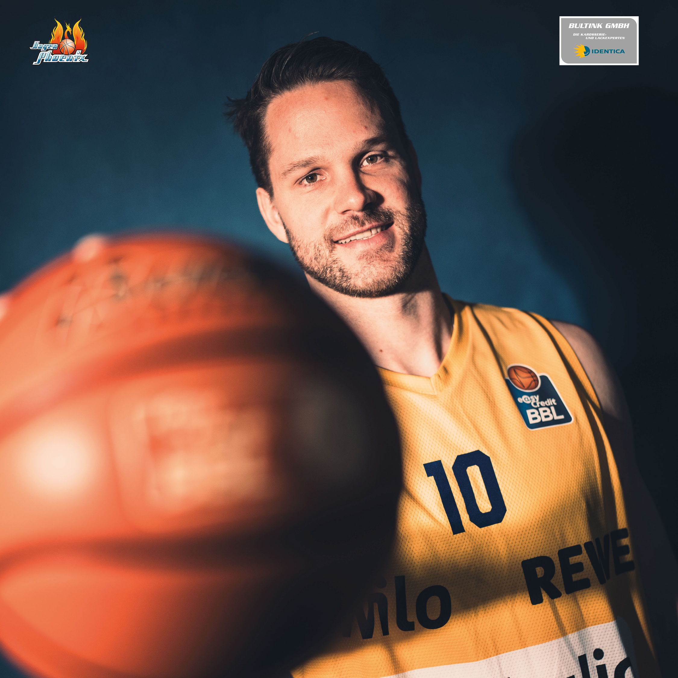 Laechelnder Basketballspieler im gelben Trikot mit Nummer zehn und Ball