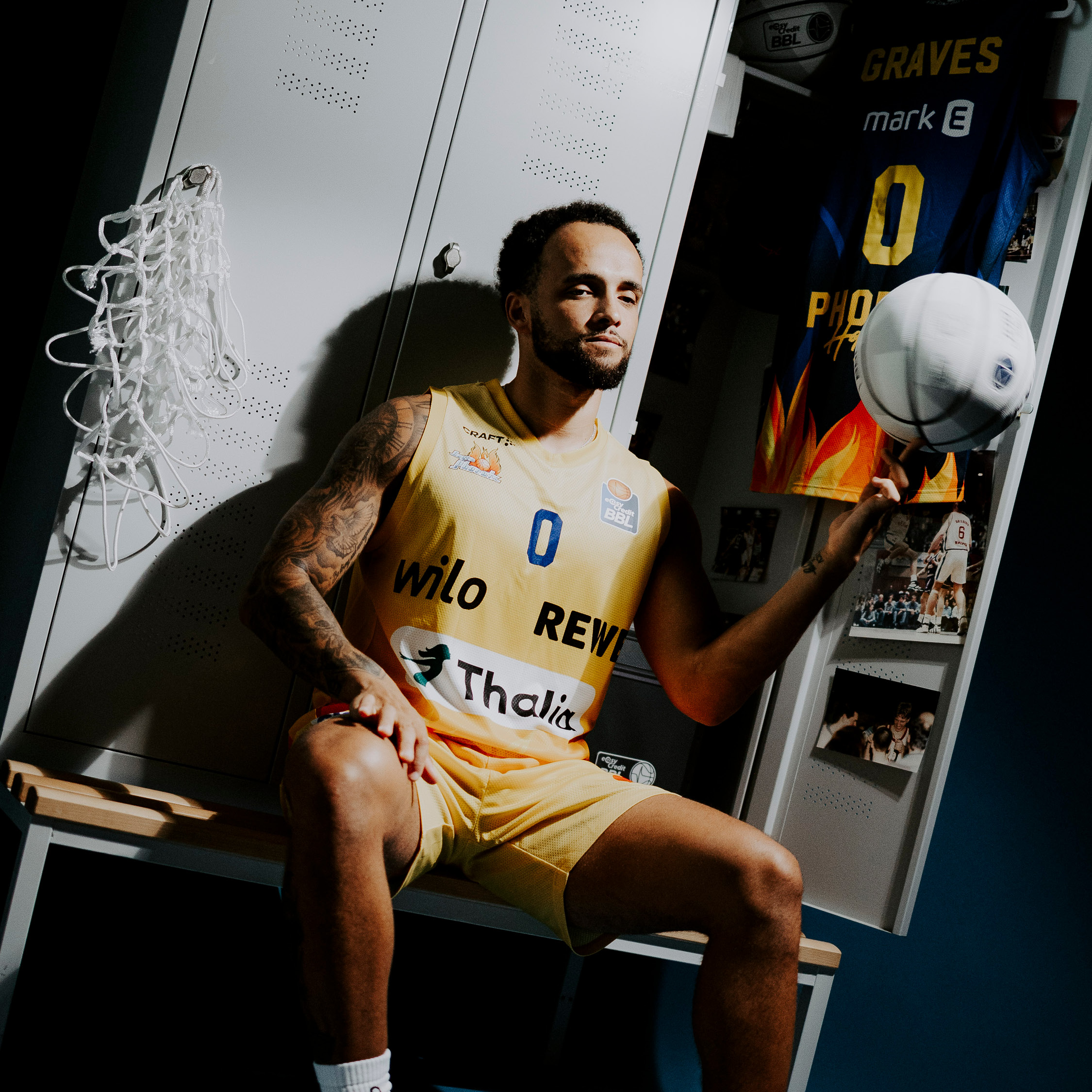 Taetowierter Basketballspieler in gelbem Trikot balanciert einen Ball auf dem Finger