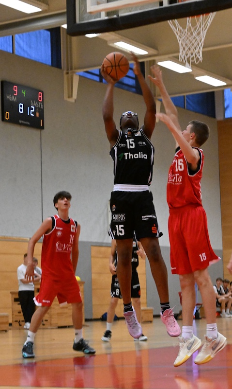Konzentrierter Basketballspieler im schwarzen Trikot beim Wurf zum Korb