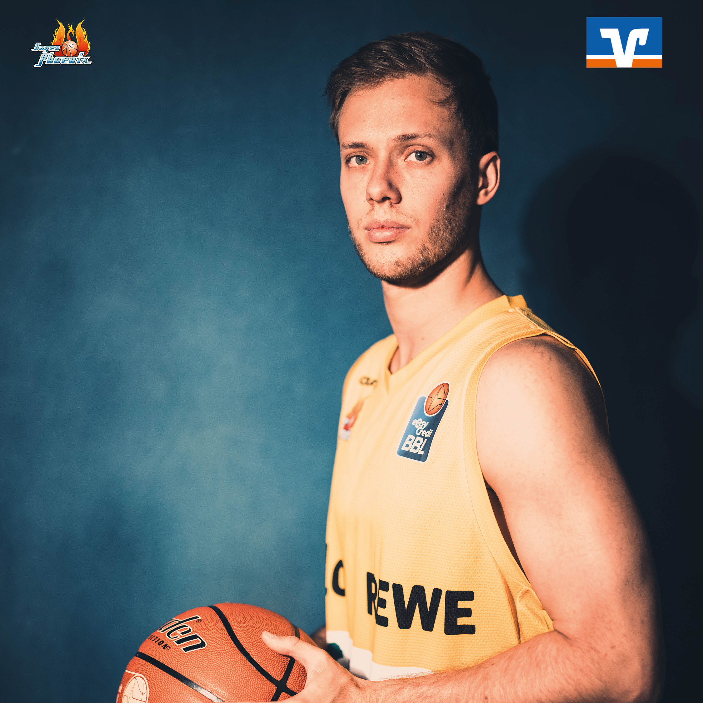 Ein ernst blickender Basketballspieler im gelben Trikot haelt einen Ball