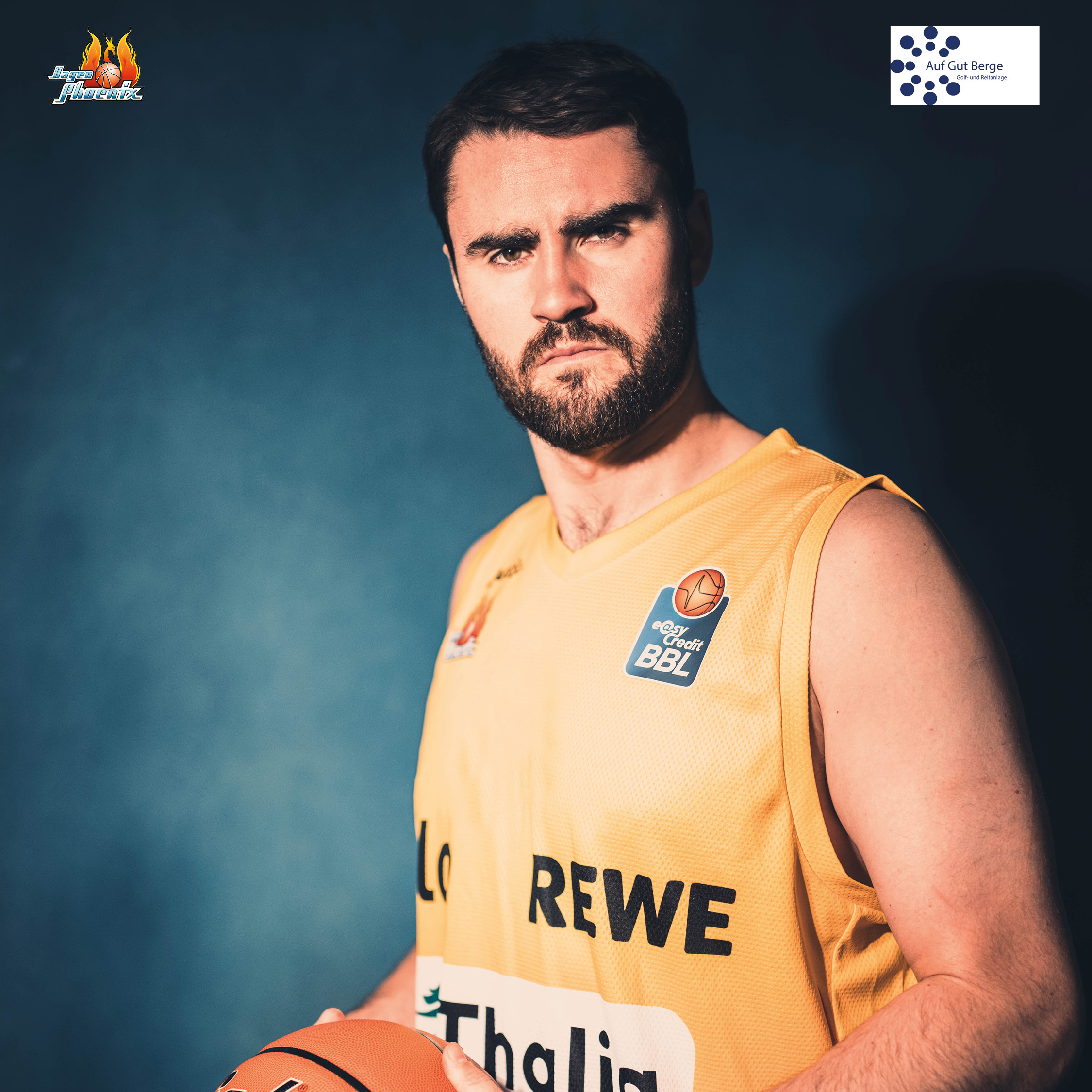 Ernst blickender baertiger Basketballspieler im gelben Trikot mit Ball