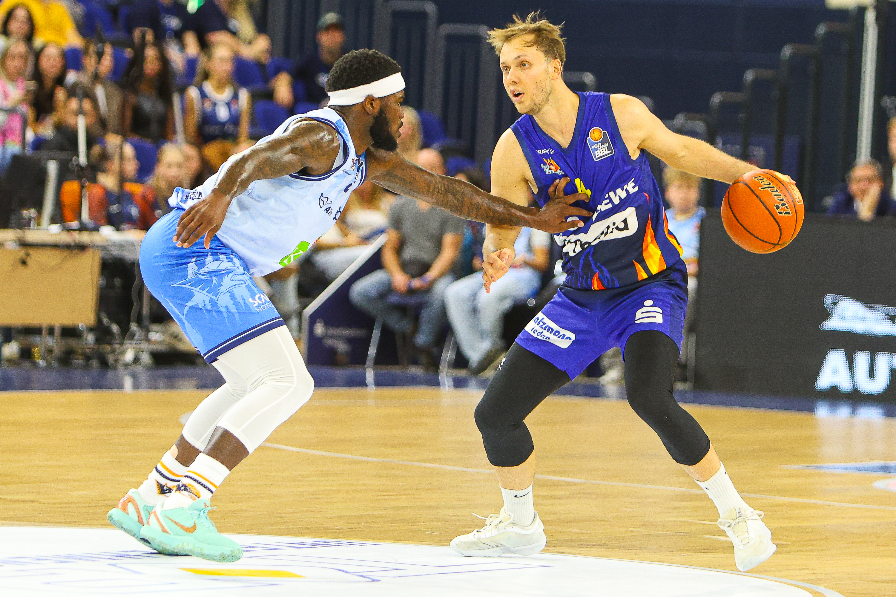 Zwei konzentrierte Basketballspieler in Blau duellieren sich um den Ball