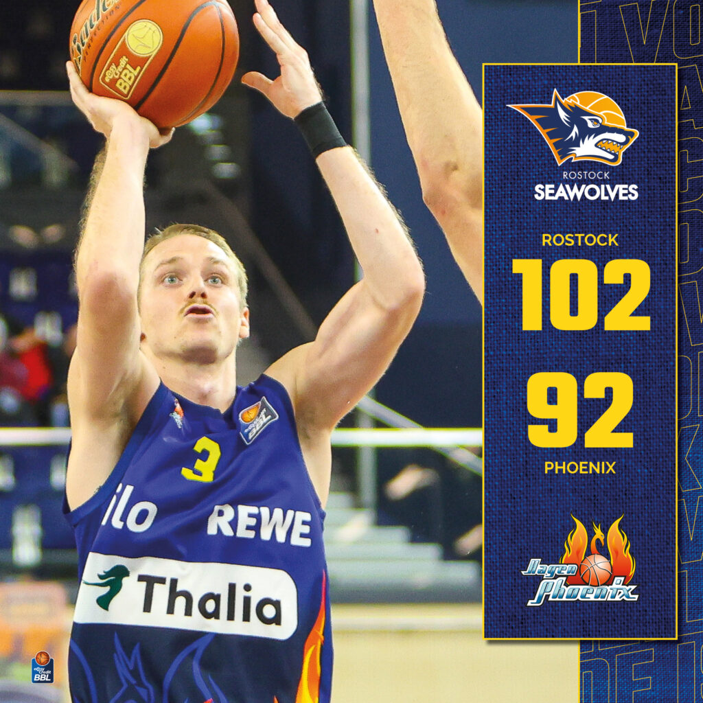 Blonder Basketballspieler im blauen Trikot wirft den Ball konzentriert zum Korb