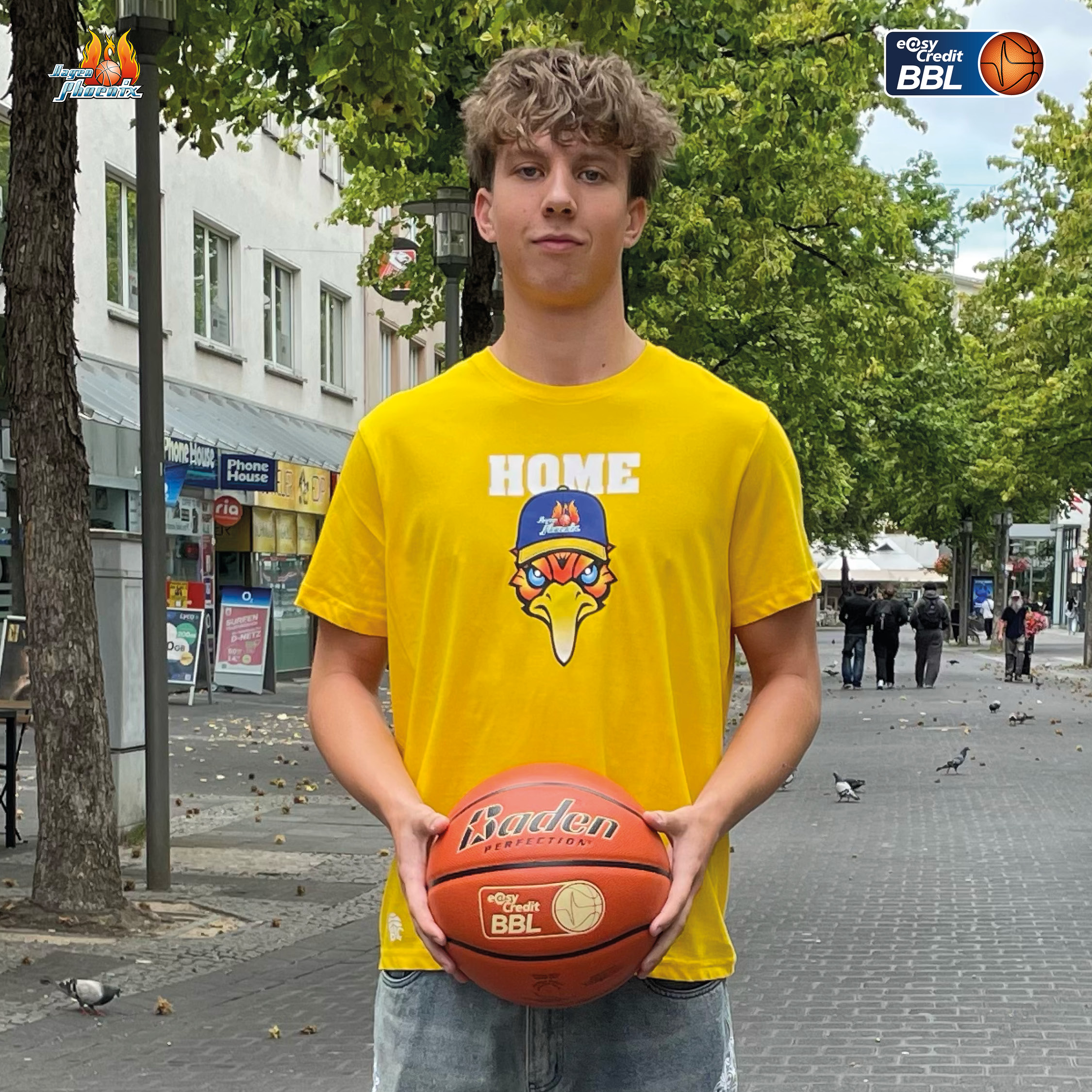 Junger Mann im gelben Phoenix Shirt haelt ernst einen Basketball auf Strasse