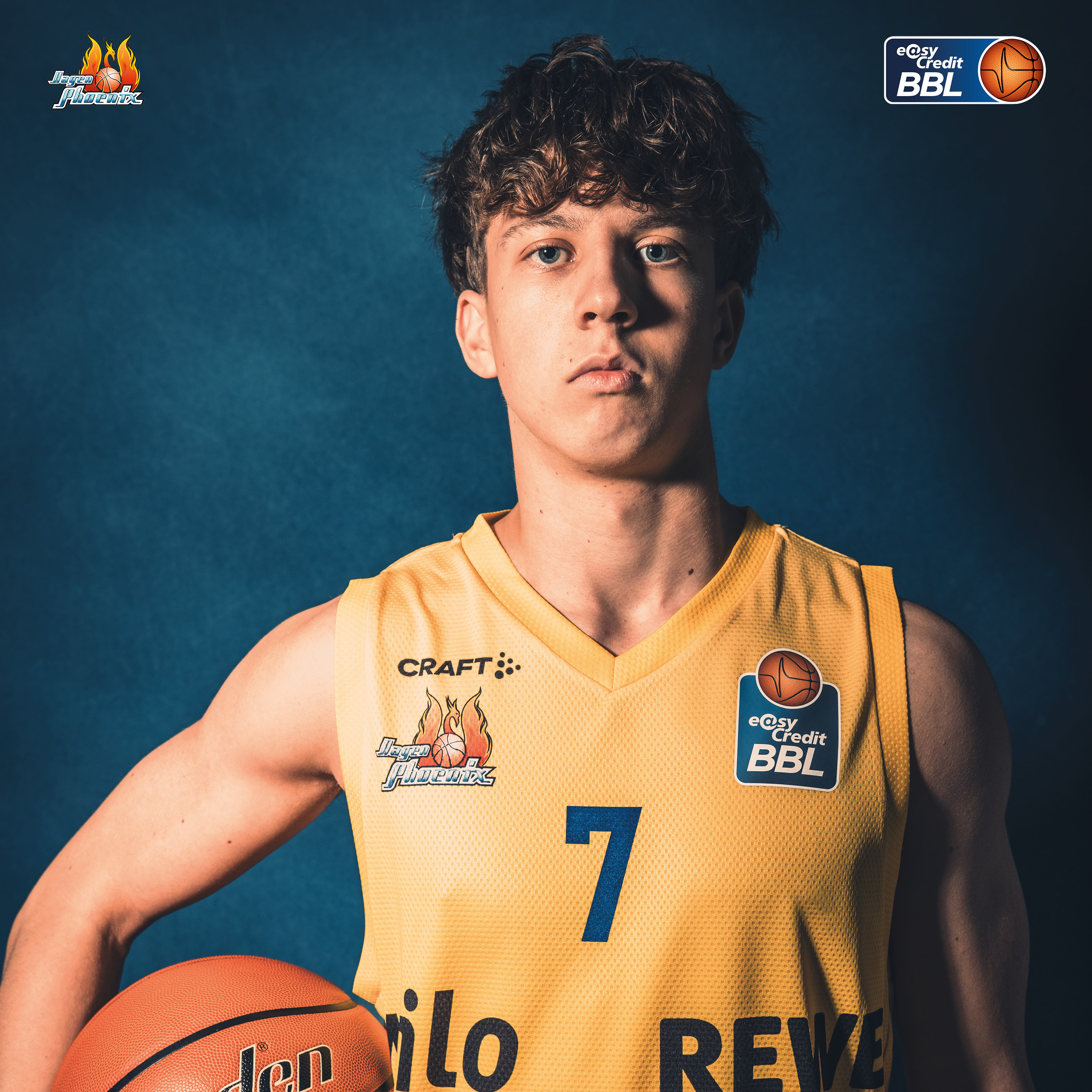 Junger Basketballspieler mit lockigem Haar im gelben Trikot mit Ball