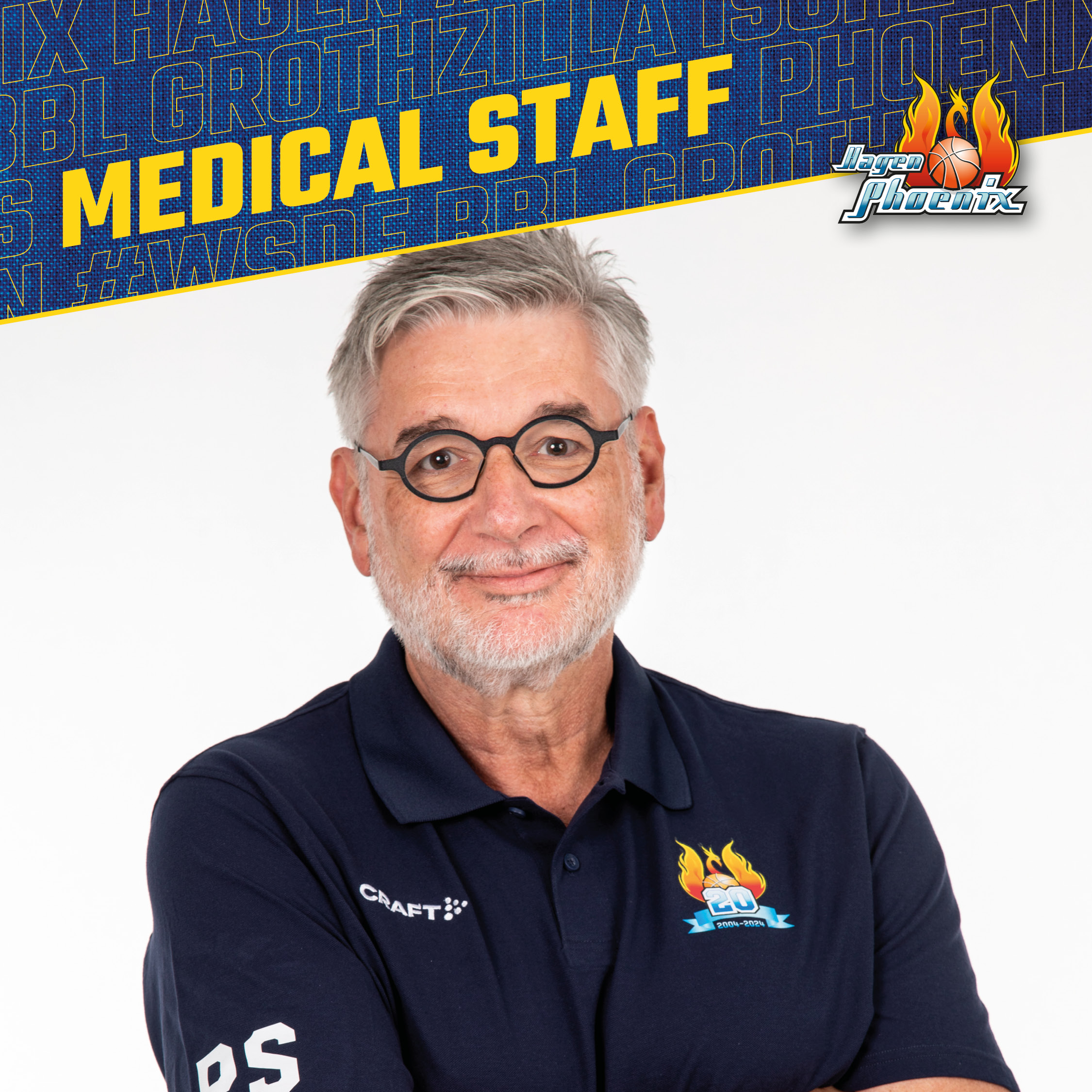Laechelnder Mann mit grauem Bart und Brille im dunkelblauen Phoenix Poloshirt
