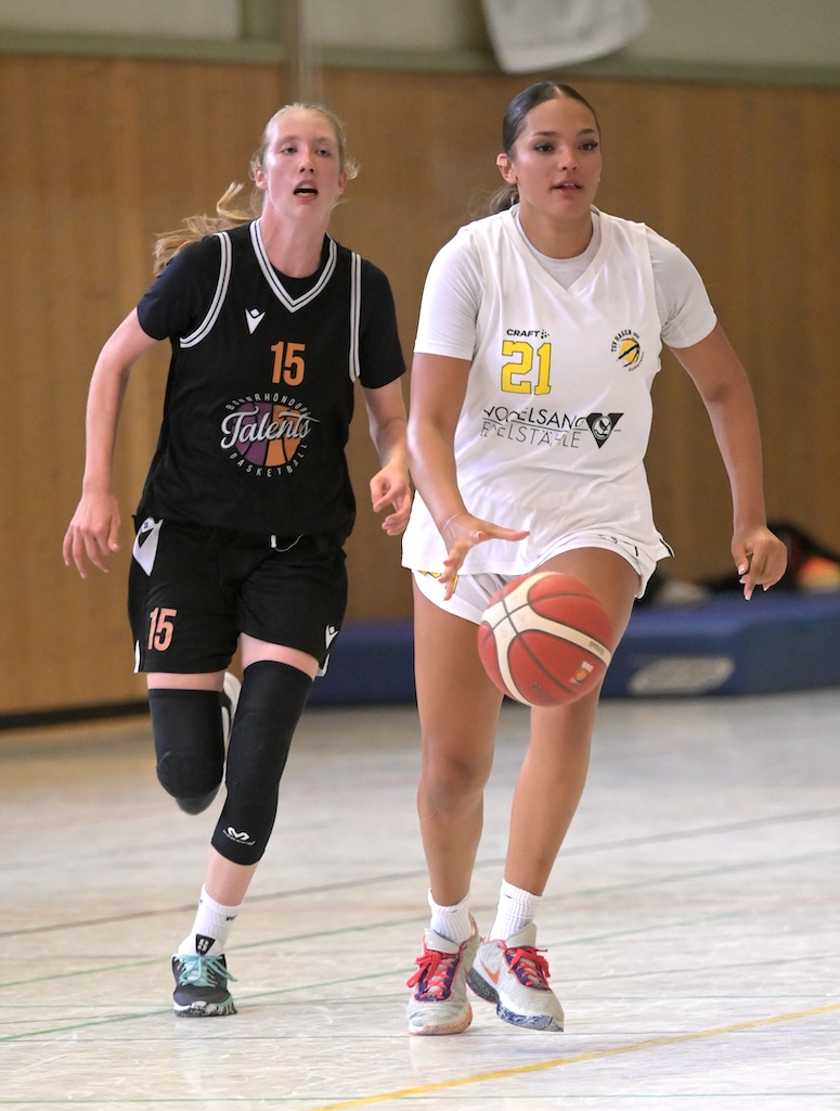 Zwei fokussierte Basketballspielerinnen in Weiss und Schwarz beim Dribbeln