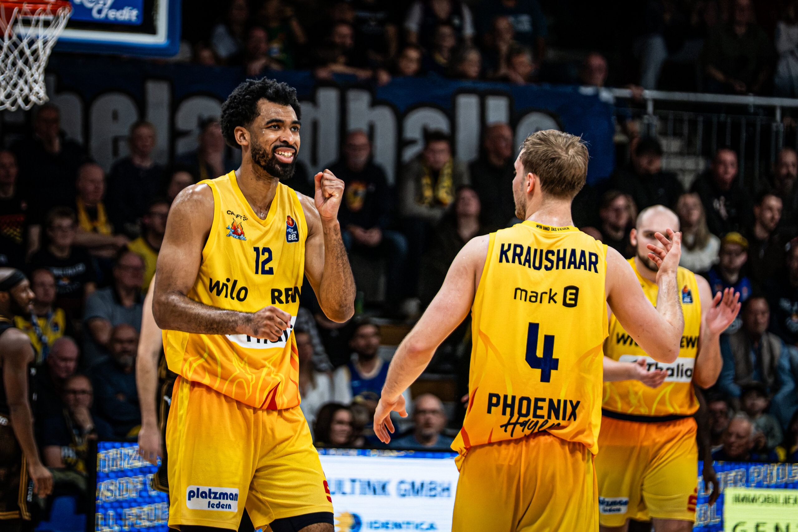 Zwei jubelnde Basketballspieler in gelben Trikots feiern gemeinsam auf dem Spielfeld