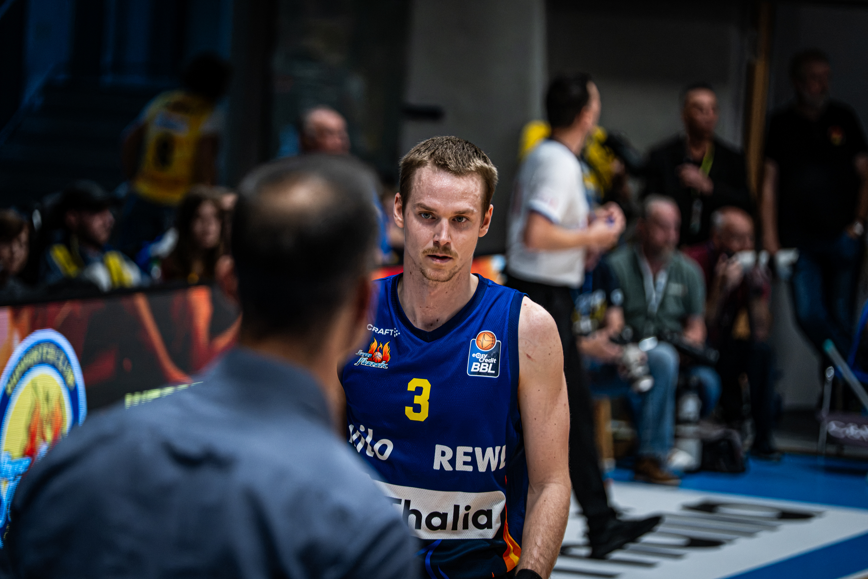 Ein fokussierter Basketballspieler im blauen Trikot mit der Nummer drei