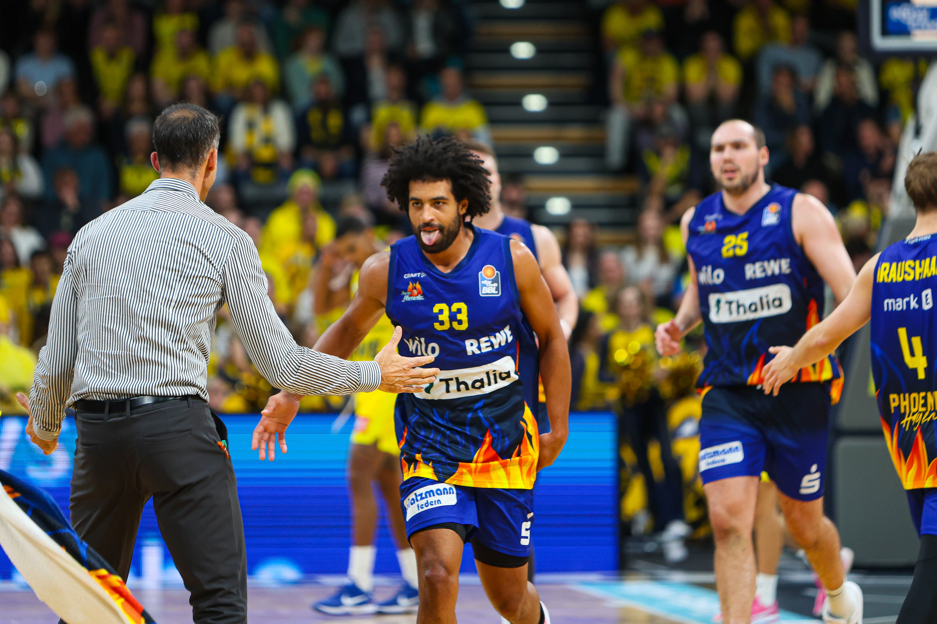 Basketballspieler mit Nummer 33 im blauen Trikot streckt jubelnd die Zunge heraus