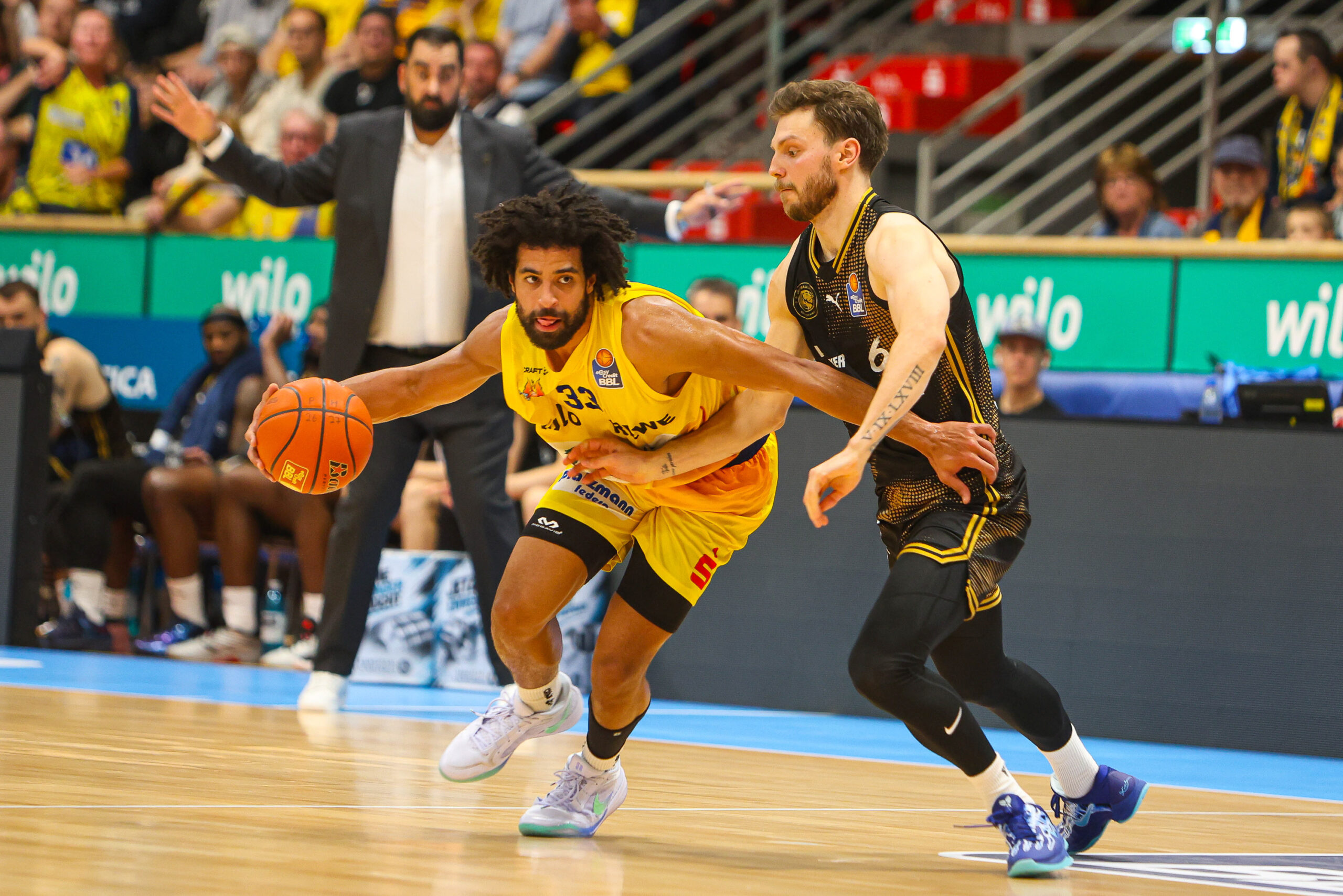 Basketballspieler im gelben Trikot dribbelt konzentriert am Gegner vorbei