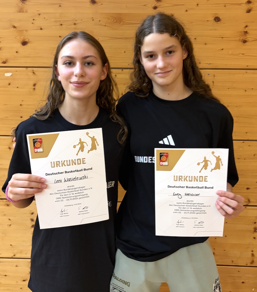 Zwei laechelnde junge Frauen in schwarzen Shirts halten Basketball Urkunden