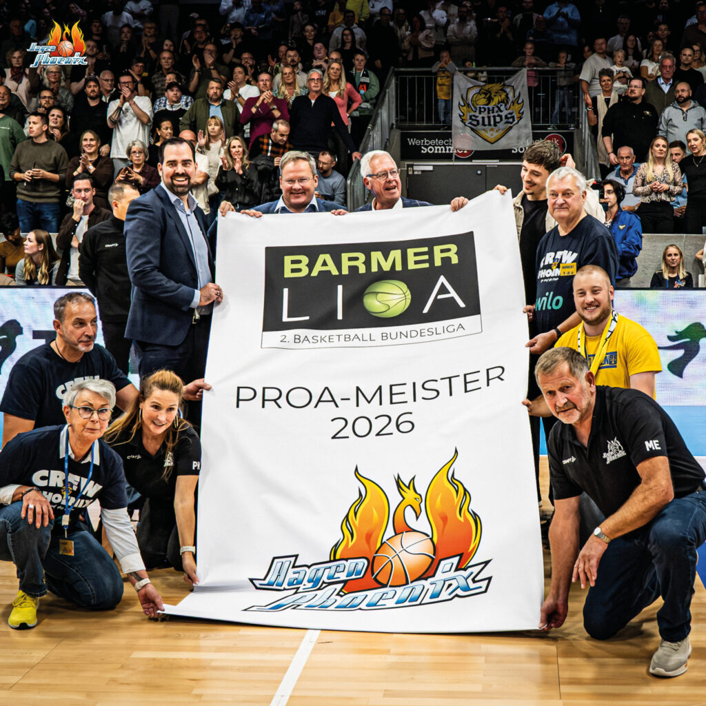 Laechelnde Personen halten stolz ein weisses ProA Meister 2026 Banner in der Halle