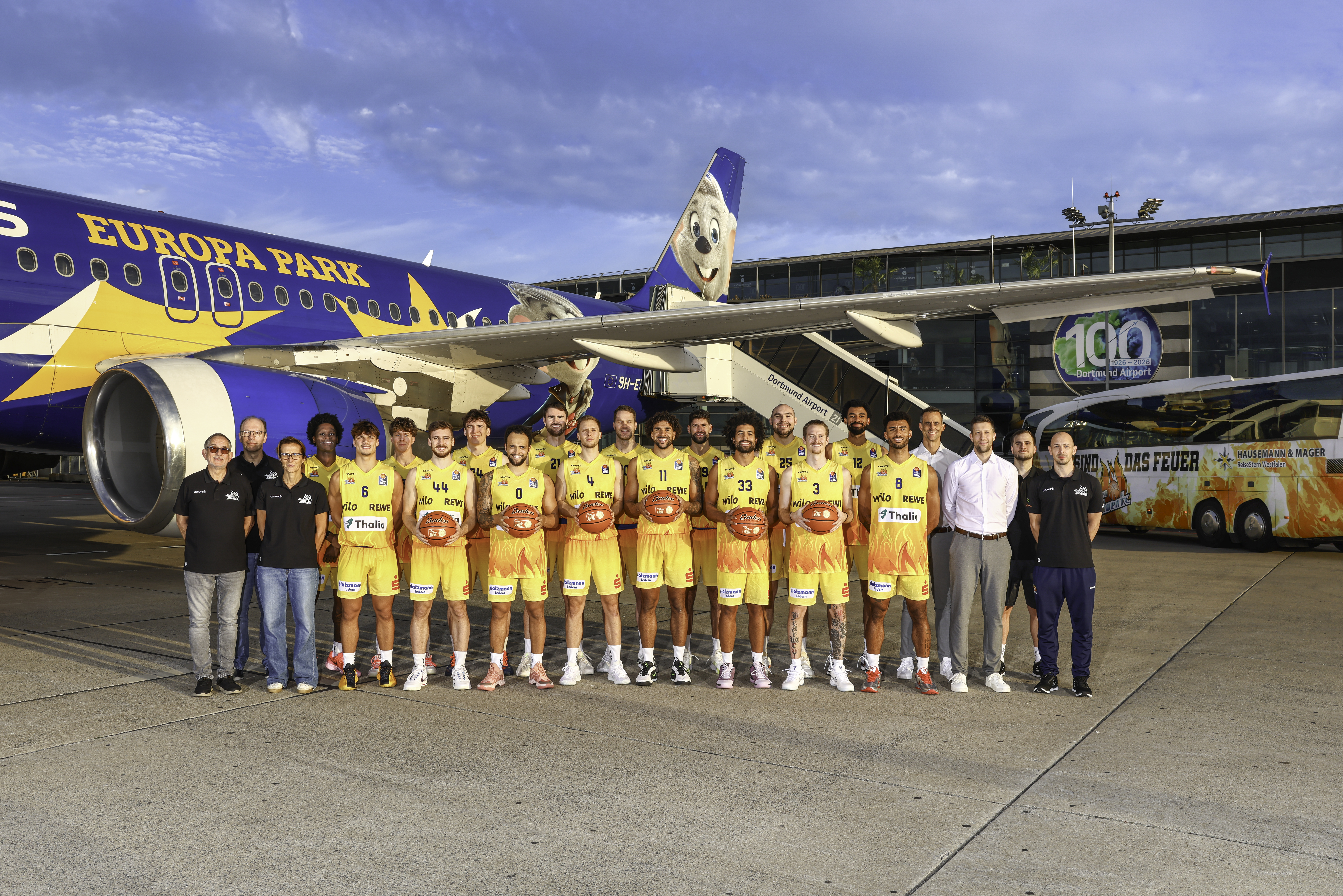 Basketballteam in gelben Trikots posiert vor einem blauen Europa Park Flugzeug