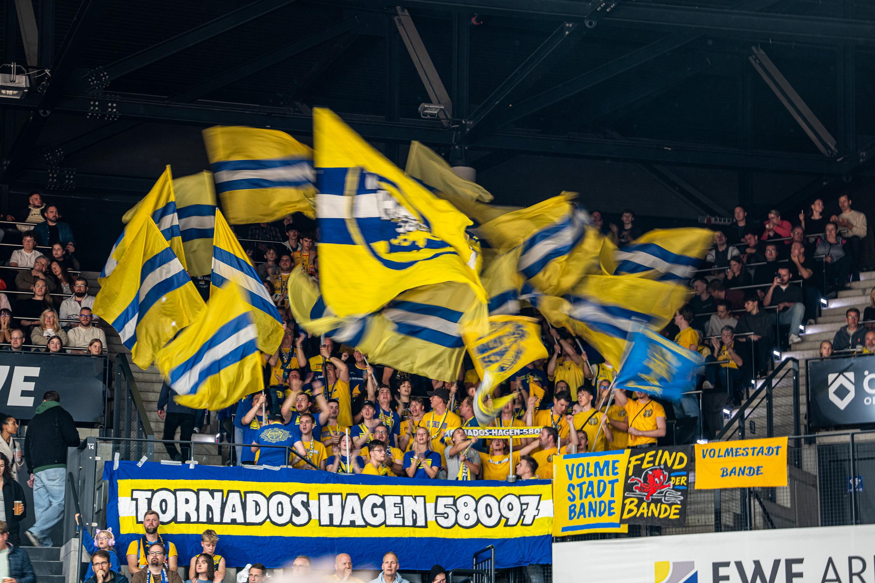 Jubelnde Fans schwenken gelb blaue Fahnen mit Banner der Tornados Hagen